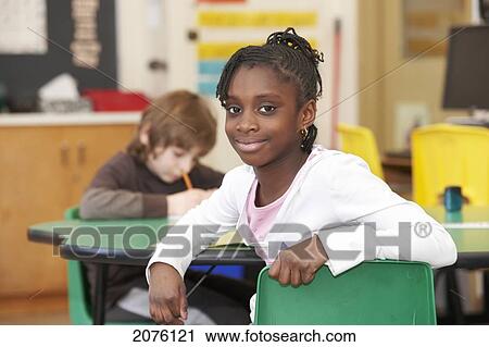 Stock Image - Young Grade 3 Girl Happy And Smiling In The Classroom; Toronto Ontario Canada. Fotosearch