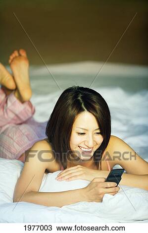Stock Image - Young Japanese Girl Communicates With Friends On Her Cell Phone.. Fotosearch