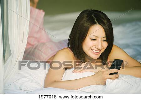 Stock Photo - Young Japanese Girl Communicates With Friends On Her Cell Phone.. Fotosearch