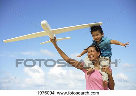 Picture - Young Japanese Girl Playing On The Beach With Her Child And Toy Airplane.. Fotosearch