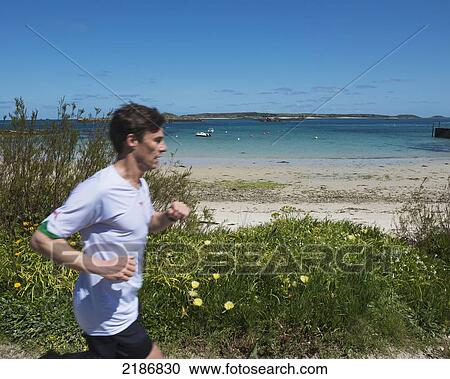 Stock Image - Young Male Jogger At Green Porth Beach. Old Grimsby, Tresco, Isles Of Scilly, Cornwall, Uk, Europe. Fotosearch