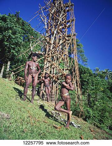 Stock Photography - Young man and boy at the base of a land diving tower; Pentecost Island, Vanuatu. Fotosearch