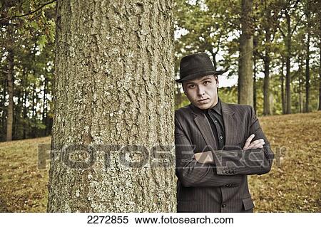 Young man in fedora leaning against a tree; hartford connecticut usa View Large Photo Image Stock Photography - Young man in fedora leaning against a tree; hartford connecticut usa. Fotosearch