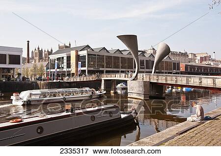 Young Man Sitting At Harborside With Pero's Bridge And Tourist Barge; Bristol, England, Uk View Large Photo Image Stock Photo - Young Man Sitting At Harborside With Pero's Bridge And Tourist Barge; Bristol, England, Uk. Fotosearch