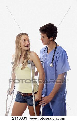 Young medical intern helps a girl with her crutches. View Large Photo Image Stock Image - Young medical intern helps a girl with her crutches.. Fotosearch