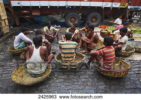 Young men sitting in baskets talking at the fruit market; Kolkata, India View Large Photo Image Stock Image - Young men sitting in baskets talking at the fruit market; Kolkata, India. Fotosearch