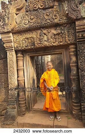Stock Image - Young monk visiting 10th Century Banteay Srei temple; Siem Reap Province, Cambodia. Fotosearch