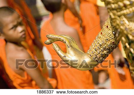 Stock Photo - Young Monks And Hand Of Gold Statue At Grand Palace. Fotosearch
