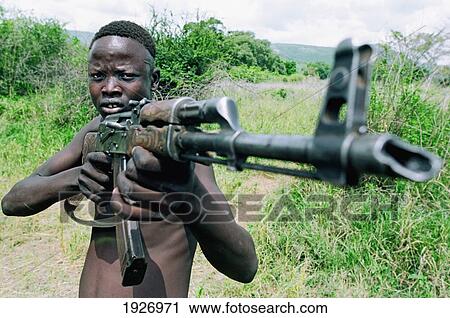 Stock Image - Young Mursi Tribal Man With Ak-47 Kalashnikov Machine Gun, Symbol Of Mursi Identity And Social Status. Fotosearch