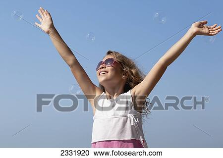 Young Smiling Girl In Sunglasses Reaching For Bubbles Against A Clear Blue Sky; Whitby Ontario Canada View Large Photo Image Stock Image - Young Smiling Girl In Sunglasses Reaching For Bubbles Against A Clear Blue Sky; Whitby Ontario Canada. Fotosearch