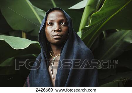Stock Photo - Young Suri boy under banana tree, Omo region, Southwest Ethiopia; Kibish, Ethiopia. Fotosearch