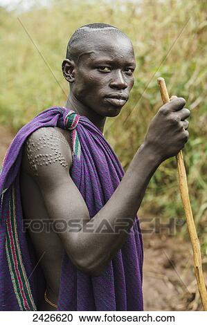 Stock Image - Young Suri (Surma) man in village of Kibish, Omo region, Southwest Ethiopia; Kibish, Ethiopia. Fotosearch