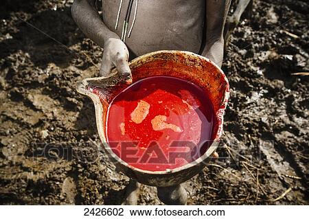 Stock Image - Young Suri (Surma) tribe cattle herder with bowl of blood taken from cow, Omo region, Southwest Ethiopia; Kibish, Ethiopia. Fotosearch