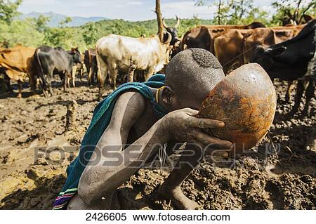 Stock Photography - Young Suri (Surma) tribe cattle herder drinking from bowl of cow's blood, Omo region, Southwest Ethiopia; Kibish, Ethiopia. Fotosearch