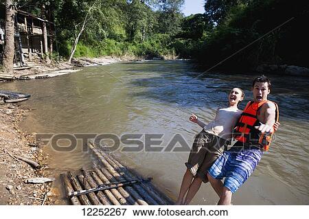 Young tourists bamboo rafting down the river; Chiang Mai, Thailand View Large Photo Image Stock Photo - Young tourists bamboo rafting down the river; Chiang Mai, Thailand. Fotosearch