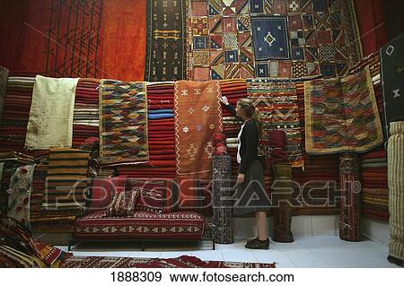 Young Woman Browsing For Moroccan Carpets And Rugs In A Market Stall In The Souk. View Large Photo Image Stock Photo - Young Woman Browsing For Moroccan Carpets And Rugs In A Market Stall In The Souk.. Fotosearch