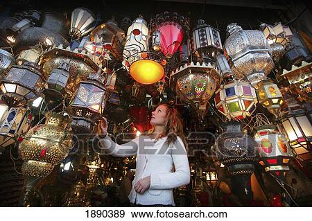 Stock Photo - Young Woman Browsing For Moroccan Lanterns In A Market Stall In The Souk.. Fotosearch