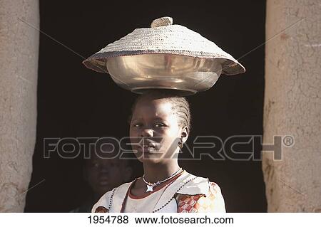 Stock Photo - Young woman carrying a pot on her head in Djenne, Mali. Fotosearch