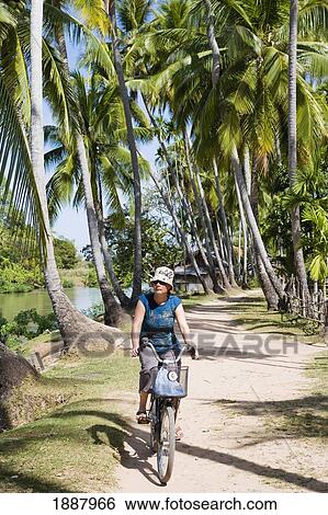 Young Woman Cycling Along The Main Road On Don Khon Island. View Large Photo Image Stock Photograph - Young Woman Cycling Along The Main Road On Don Khon Island.. Fotosearch