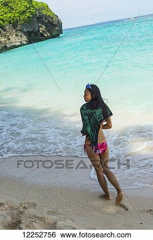 Stock Photograph - Young woman enjoys walking on the sand of Puka beach; Borakay, Panay, Philippines. Fotosearch