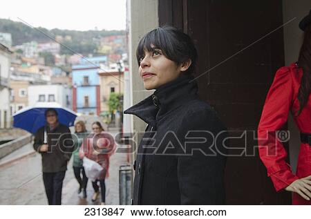 Young woman hiding from rain at store display; Guanajuato, Guanajuato, Mexico View Large Photo Image Stock Photo - Young woman hiding from rain at store display; Guanajuato, Guanajuato, Mexico. Fotosearch
