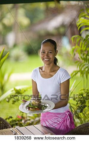 Stock Photo - Young Woman Holding Plate With Food, Portrait; Dumaguete, Oriental s Island, Philippines. Fotosearch