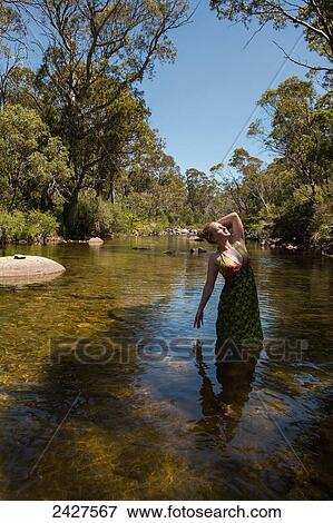 Stock Photo - Young woman in a creek doing yoga poses; Threadbo, New South Wales, Australia. Fotosearch