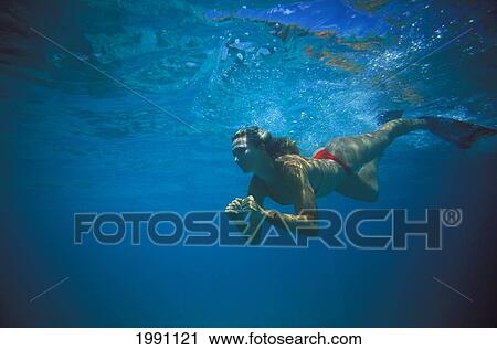 Stock Image - Young Woman In Bikini Swimming Underwater With Fins. Fotosearch
