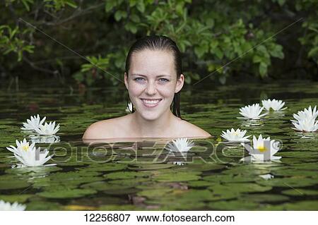 Stock Photo - Young woman in water among the water lilies; Connecticut, United States of America. Fotosearch