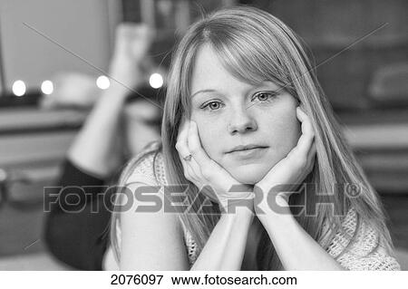Stock Photo - Young Woman Laying On Her Stomach With Her Head Propped Up With Her Hands. Fotosearch