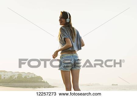 Young woman listening to music with her headphones on the beach; Xiamen, China View Large Photo Image Stock Image - Young woman listening to music with her headphones on the beach; Xiamen, China. Fotosearch