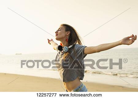 Young woman listening to music with her headphones on the beach; Xiamen, China View Large Photo Image Stock Photo - Young woman listening to music with her headphones on the beach; Xiamen, China. Fotosearch
