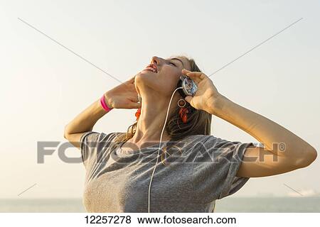 Young woman listening to music with her headphones on the beach; Xiamen, China View Large Photo Image Stock Photo - Young woman listening to music with her headphones on the beach; Xiamen, China. Fotosearch
