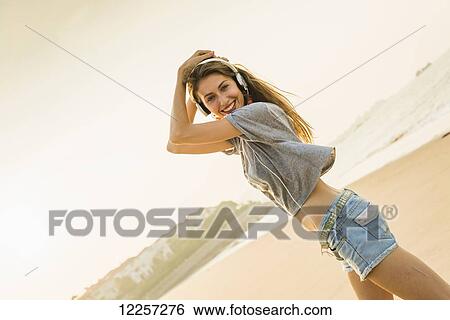 Young woman listening to music with her headphones on the beach; Xiamen, China View Large Photo Image Stock Photograph - Young woman listening to music with her headphones on the beach; Xiamen, China. Fotosearch