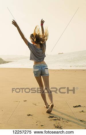 Stock Photography - Young woman listening to music with her headphones on the beach; Xiamen, China. Fotosearch