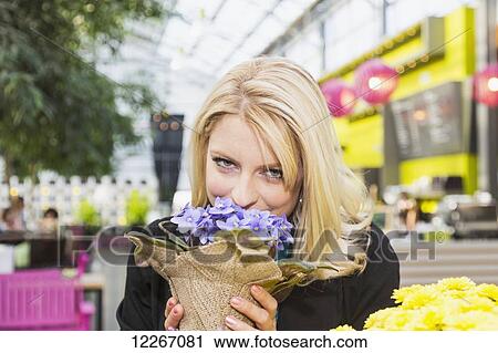 Stock Image - Young woman looking at potted plants in a greenhouse store inside a mall; St. Albert, Alberta, Canada. Fotosearch