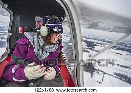 Young woman looking out of a window in the back of a small airplane flying over Lancaster county; Pennsylvania, United States of America View Large Photo Image Stock Photo - Young woman looking out of a window in the back of a small airplane flying over Lancaster county; Pennsylvania, United States of America. Fotosearch