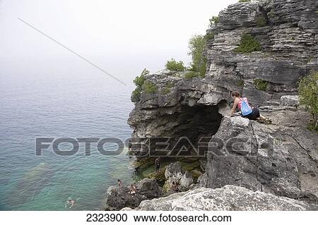 Young woman looking over cliff to swimmers below in Bruce Peninsula National Park; Ontario, Canada View Large Photo Image Stock Image - Young woman looking over cliff to swimmers below in Bruce Peninsula National Park; Ontario, Canada. Fotosearch