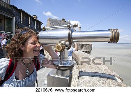 Young woman looking through a telescope on the walls of Mont Saint Michel, Normandy, France View Large Photo Image Stock Photograph - Young woman looking through a telescope on the walls of Mont Saint Michel, Normandy, France. Fotosearch