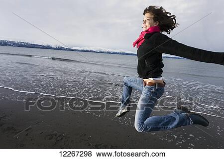 Stock Photo - Young woman playing and jumping on the Homer Spit, Kenai Peninsula, Southcentral Alaska. Fotosearch