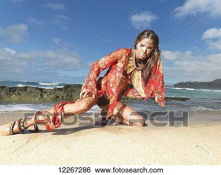 Stock Photograph - Young woman posing on a beach in a bikini and tribal face paint; Kauai, Hawaii, United States of America. Fotosearch