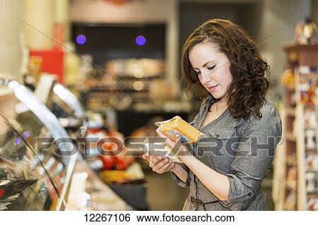 Stock Photograph - Young woman shopping in organic market for her groceries; St. Albert, Alberta, Canada. Fotosearch
