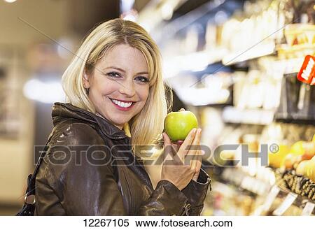 Stock Photography - Young woman shopping in organic market for her groceries; St. Albert, Alberta, Canada. Fotosearch