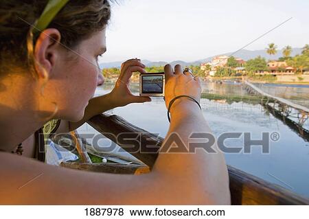Stock Photo - Young Woman Sitting At A Bar Overlooking The Nam Song River.. Fotosearch