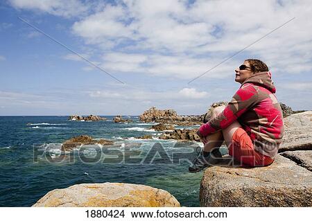 Young Woman Sitting Looking Out To Sea On Rocky Shoreline In Brittany View Large Photo Image Picture - Young Woman Sitting Looking Out To Sea On Rocky Shoreline In Brittany. Fotosearch