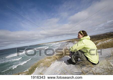 Stock Image - Young Woman Sitting On Beach. Fotosearch