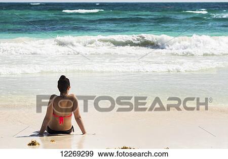 Young woman sitting on sandy beach in water looking out at waves coming in and blue sky; Akumal, Quintana Roo, Mexico View Large Photo Image Stock Photo - Young woman sitting on sandy beach in water looking out at waves coming in and blue sky; Akumal, Quintana Roo, Mexico. Fotosearch