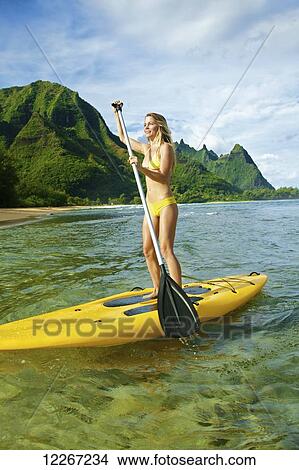 Picture - Young woman stand up paddle boarding; Kauai, Hawaii, United States of America. Fotosearch