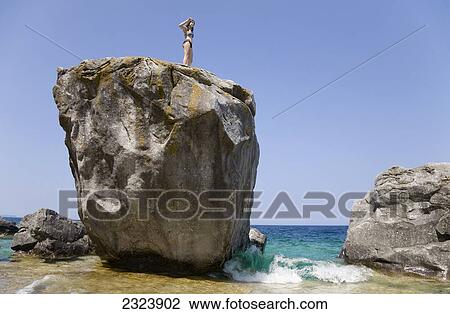 Young woman standing high up on a large rock on beach in Bruce Peninsula National Park; Ontario, Canada View Large Photo Image Stock Image - Young woman standing high up on a large rock on beach in Bruce Peninsula National Park; Ontario, Canada. Fotosearch