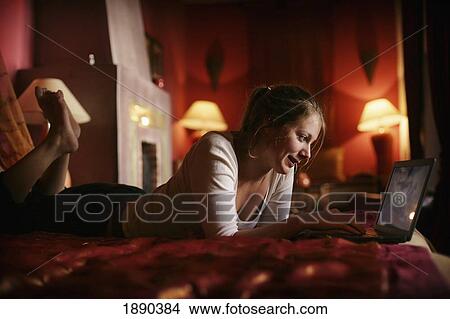 Picture - Young Woman Surfing The Internet On Her Laptop On The Bed In A Riad (Ryad).. Fotosearch